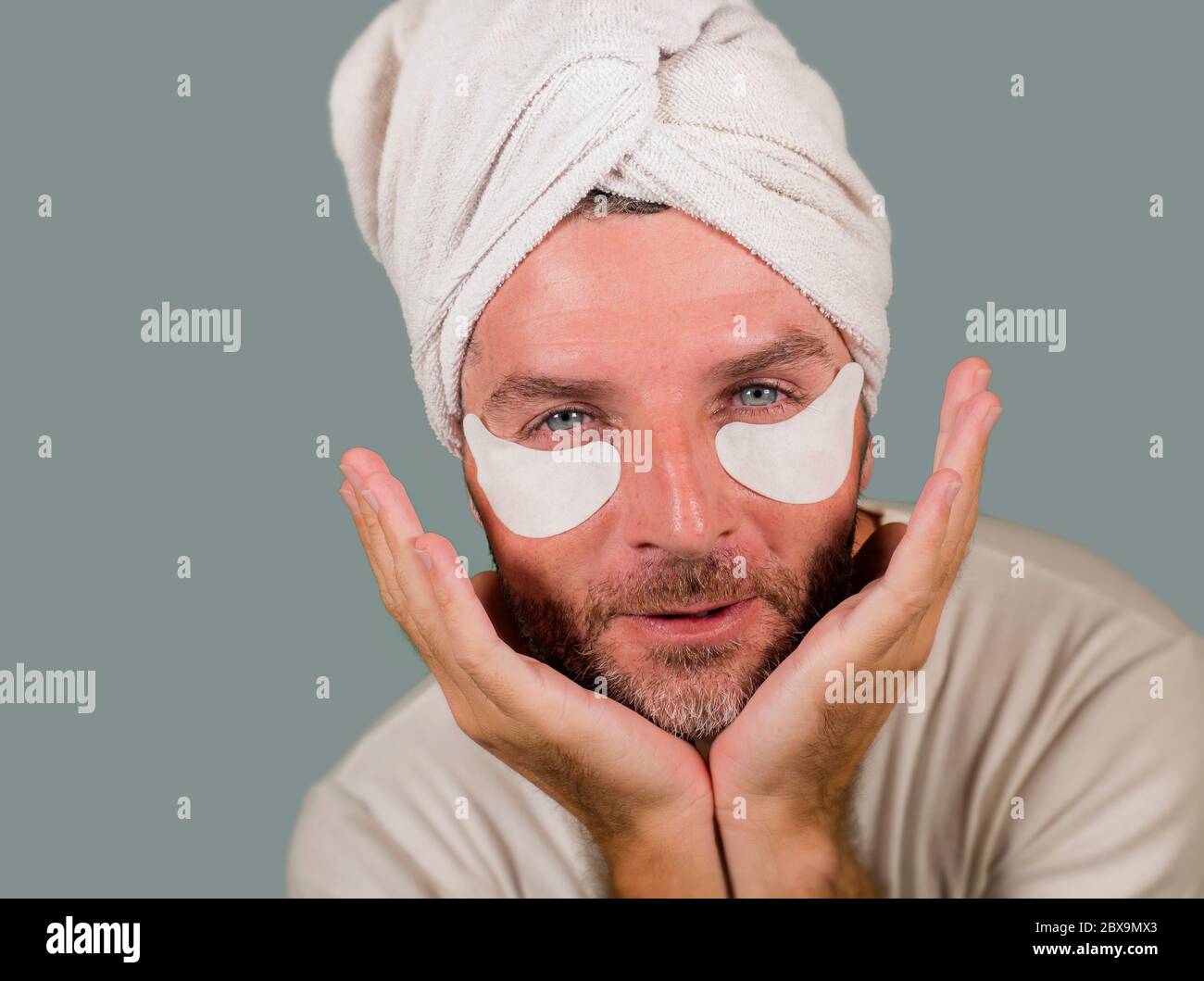 funny isolated face portrait of young happy and attractive camp gay man  applying moisturizer eye patch facial product with head wrapped towel in  masc Stock Photo - Alamy