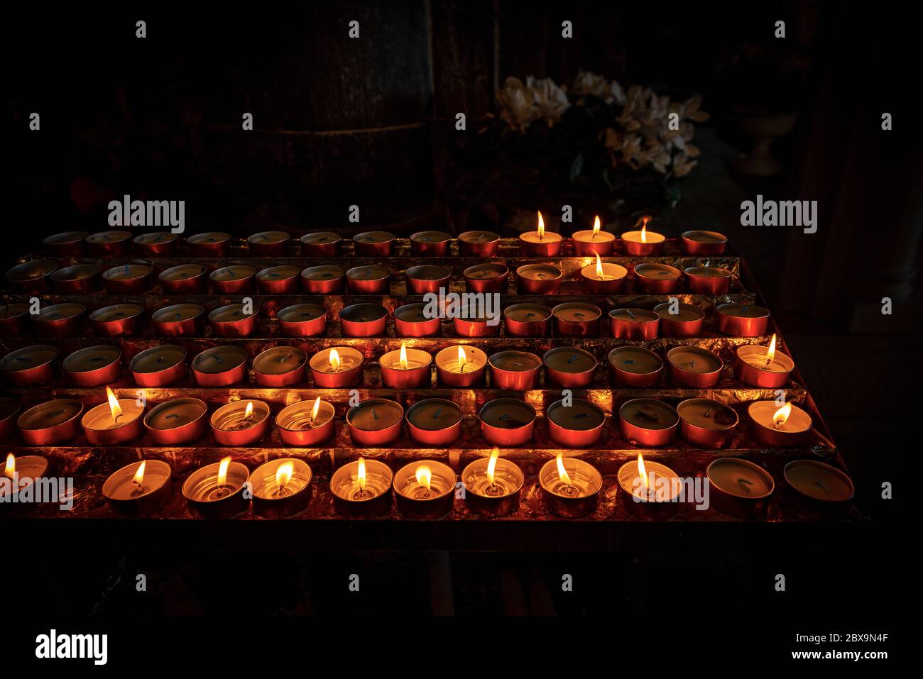 Closeup of votive candles, tea lights, in a dark Christian church. Italy, Europe Stock Photo