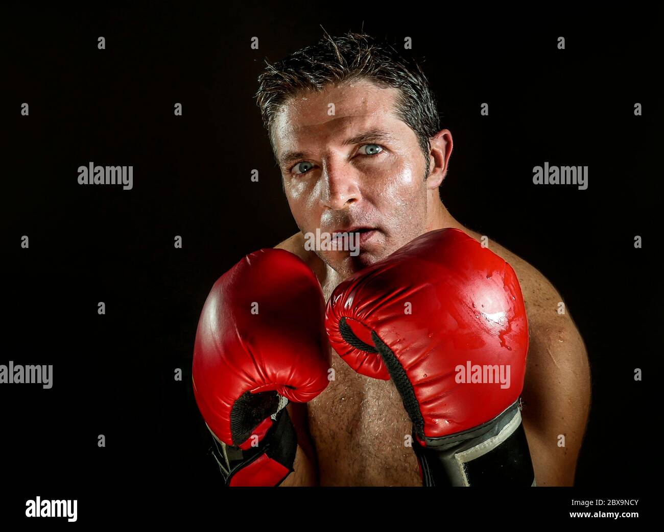 young angry and fierce sport man in boxing gloves posing in badass
