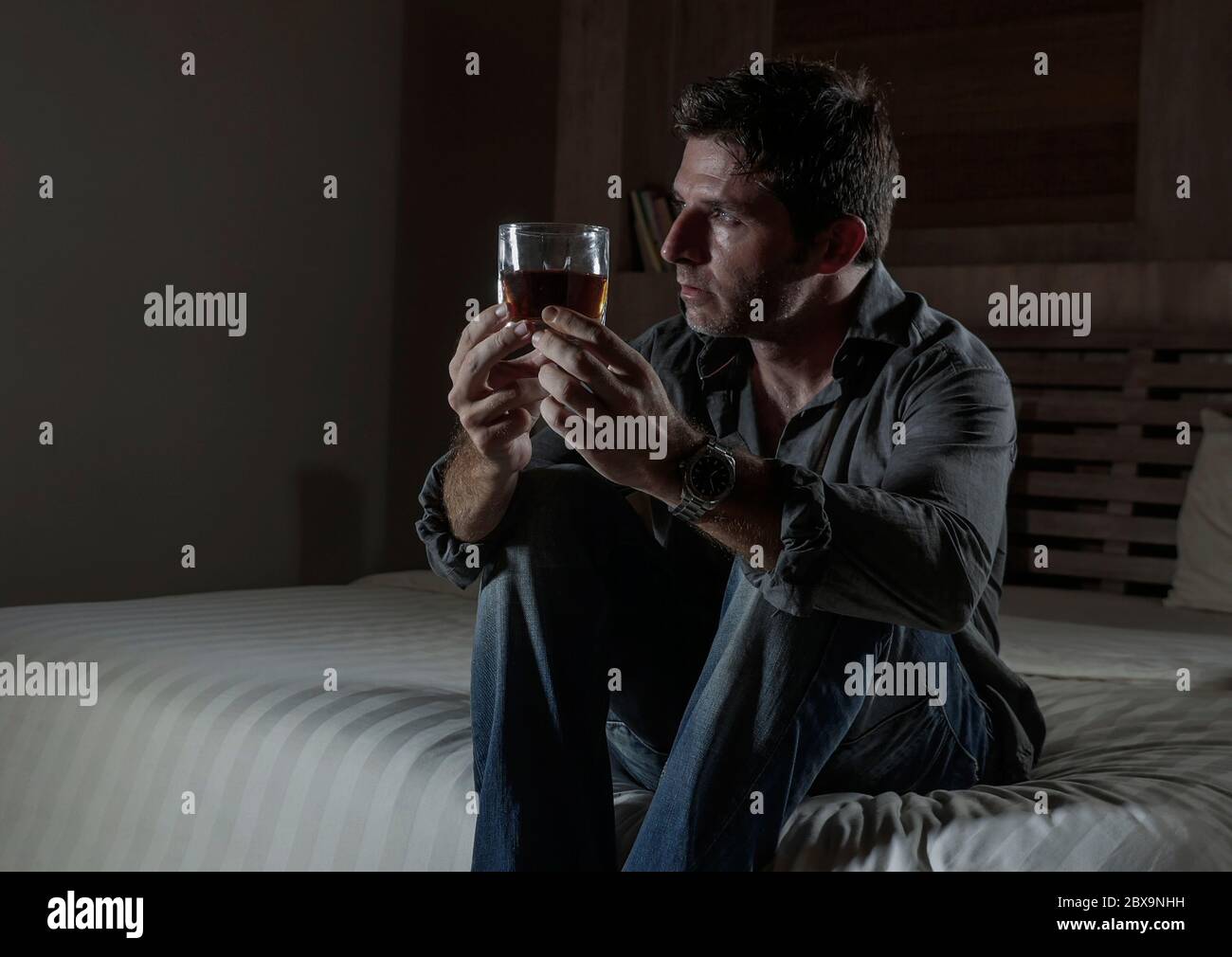 young messy and wasted drunk man drinking whiskey glass at home sitting