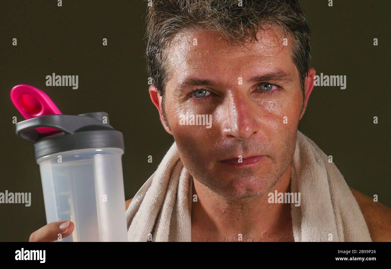 head and shoulders portrait of young attractive and handsome sport man sweating after gym workout training hard looking sweaty and defiant with towel Stock Photo