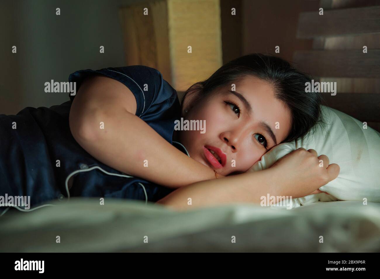 home lifestyle portrait of young beautiful sad and depressed Asian Chinese woman awake in bed late night suffering anxiety crisis and depression probl Stock Photo
