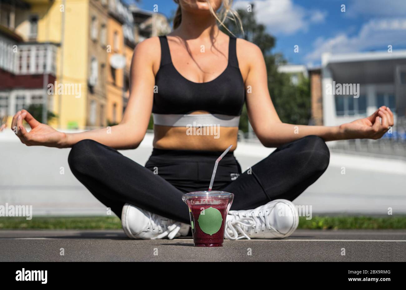 Woman sitting on the floor in lotus position with a glass of blueberry ...