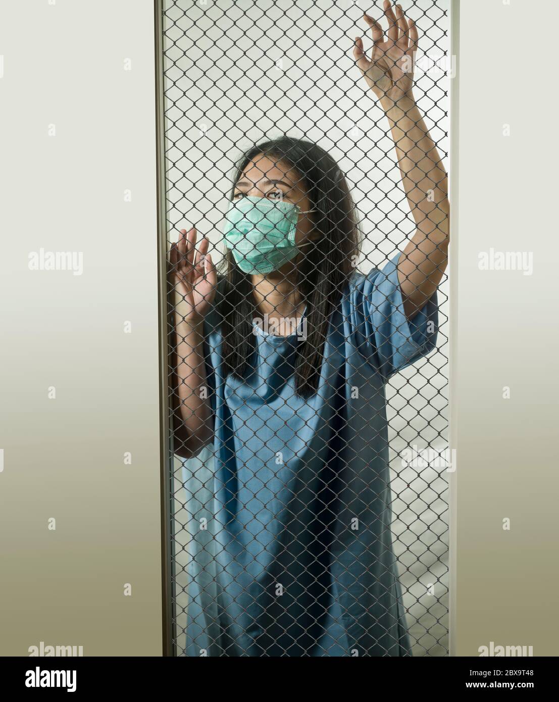 dramatic portrait of young Asian Chinese woman infected with virus victim of contagious disease or psychotic and mental insane patient locked in secur Stock Photo