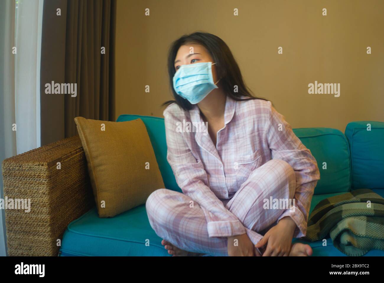Quarantine And Home Lockdown Young Beautiful Stressed And Worried Asian Korean Woman In Pajamas On Couch In Surgical Mask Feeling Sad And Scared Abo Stock Photo Alamy