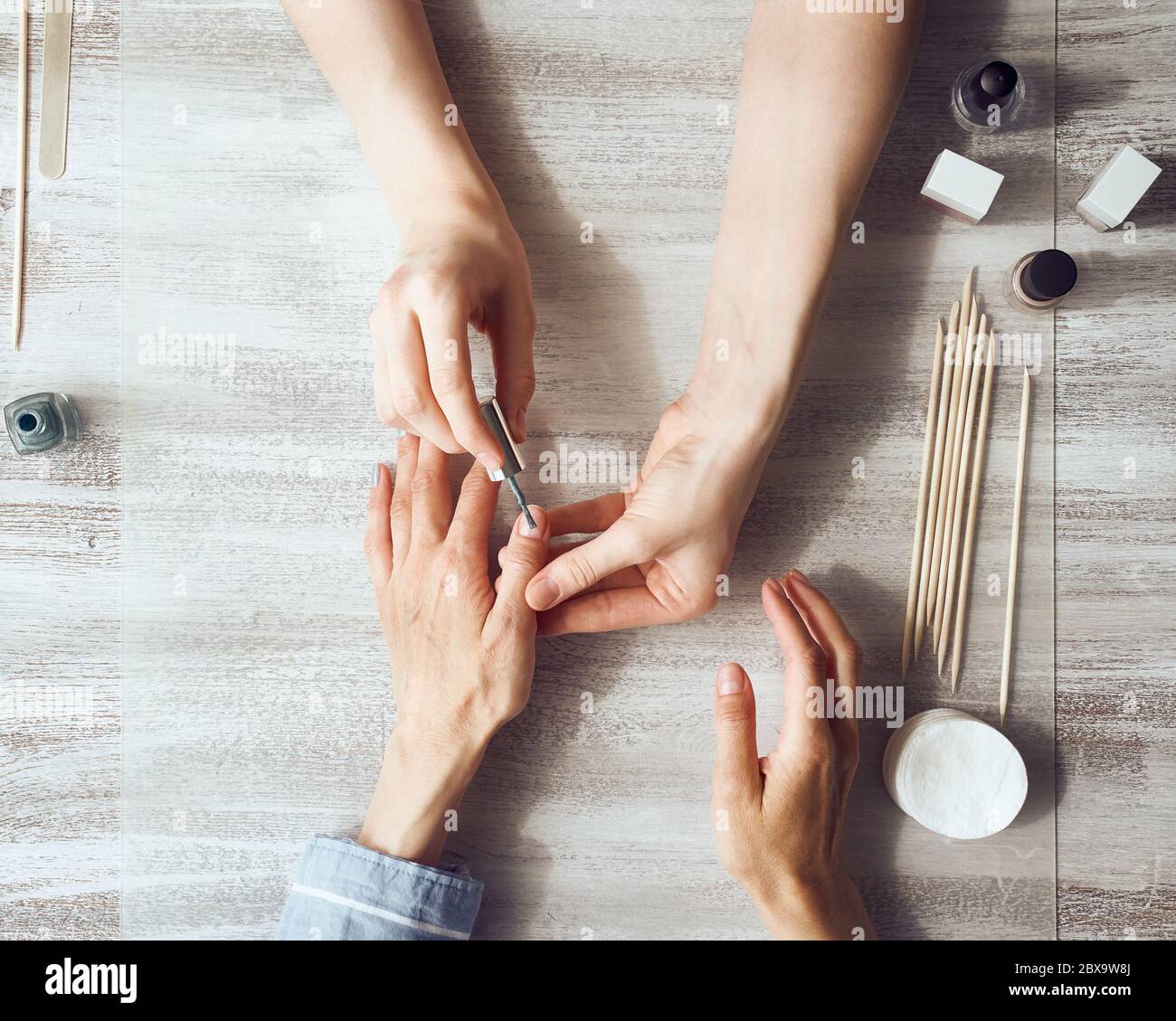 Mother and daughter do manicure, paint nails with varnish. Home self-care during quarantine Stock Photo