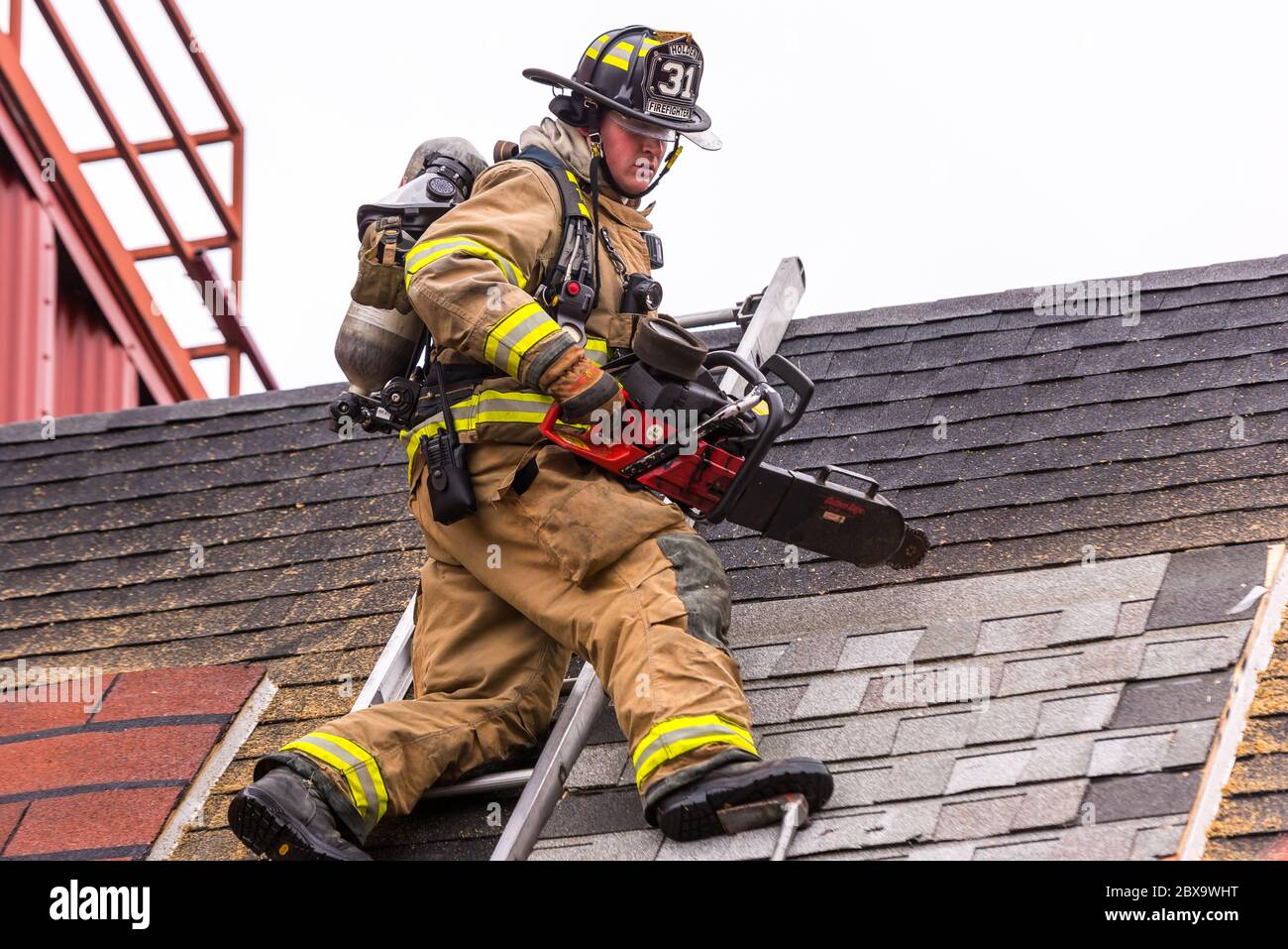 Firefighter standing on a roof during with a saw during firefighter training at the Worcester