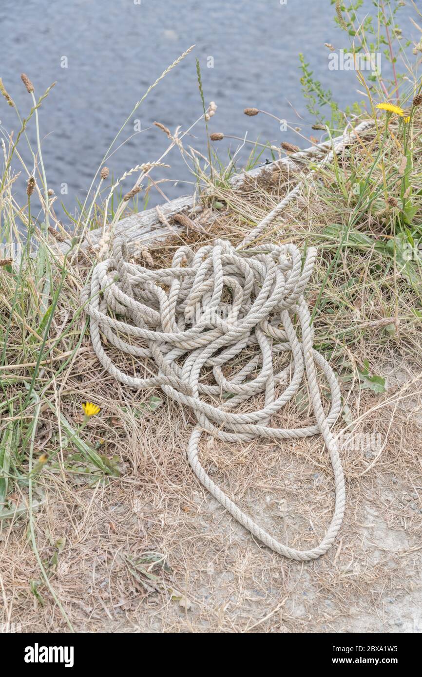 Boat mooring ropes coiled on quayside of a river. Metaphor boating, outdoor activities, sailing. Stock Photo