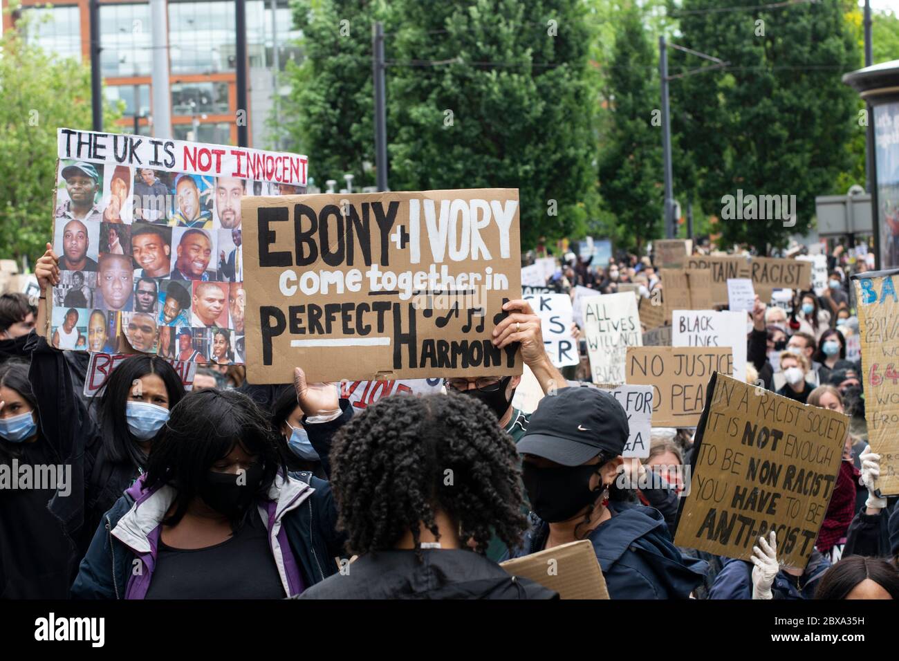 Black Lives Matter Protest Manchester UK. Protesters leave Piccadilly Gardens for Market Street. Woman holds up sign text Ebony and Ivory Stock Photo
