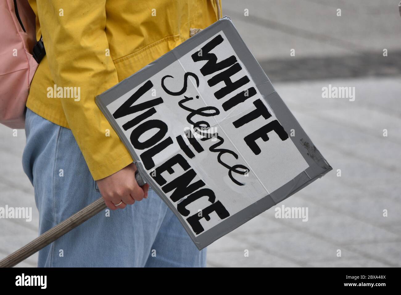 A young caucasian woman protests at a British anti racism rally in the UK holding a sign that reads 'White Silence Equals Violence'' Stock Photo