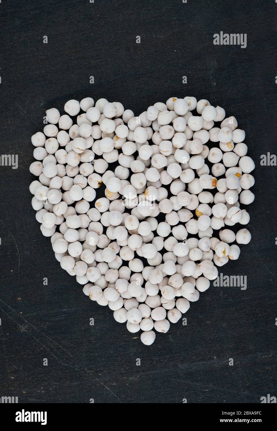 Heart shaped white roasted chickpeas on black background Stock Photo