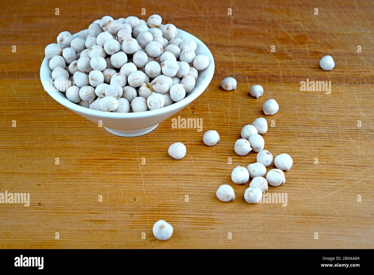 Plateful of Organic White chickpeas and Spilled White chickpeas on Wooden Background Stock Photo
