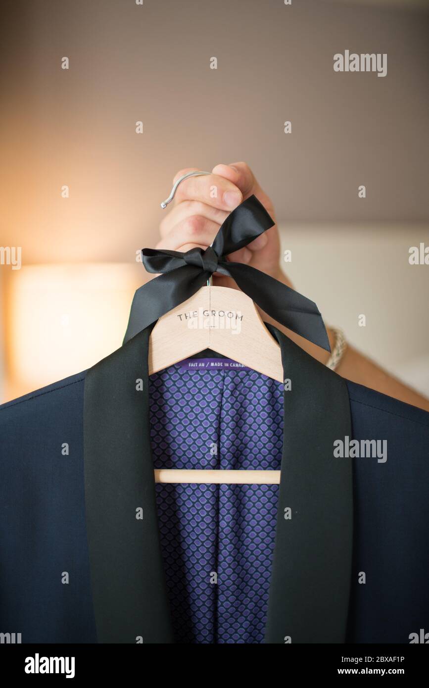Groom holding suit on hanger with a black bow Stock Photo