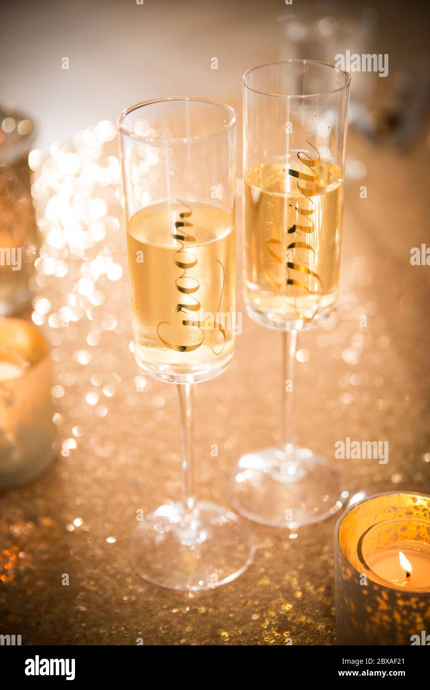 Bride and groom champagne flutes on sparkling gold table setting Stock Photo