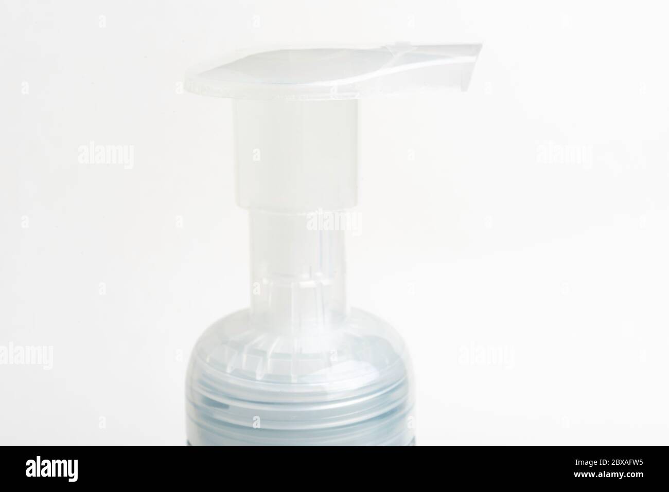 A close-up image of the translucent top pump of a foam soap plastic bottle dispenser set on a white background. Stock Photo