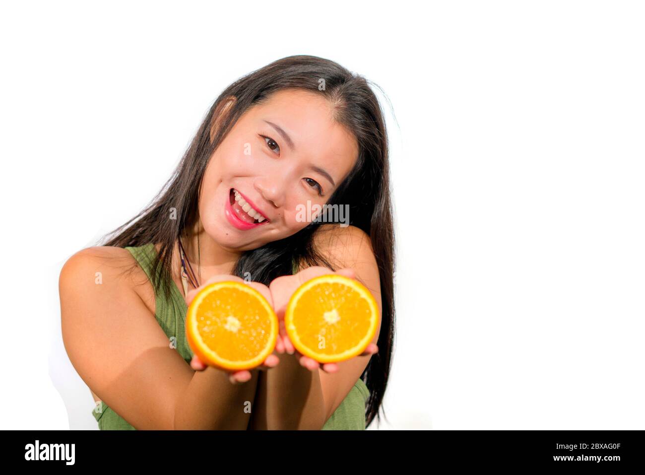 young beautiful and happy Asian Japanese woman holding orange fruit ...