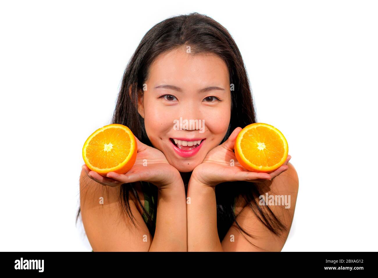 young beautiful and happy Asian Korean woman holding orange fruit ...