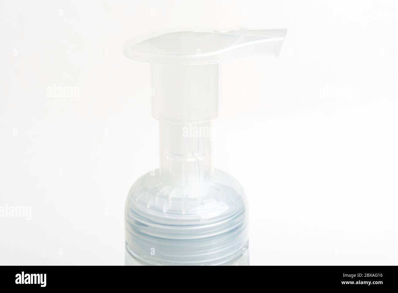 A close-up image of the translucent top pump of a foam soap plastic bottle dispenser set on a white background. Stock Photo