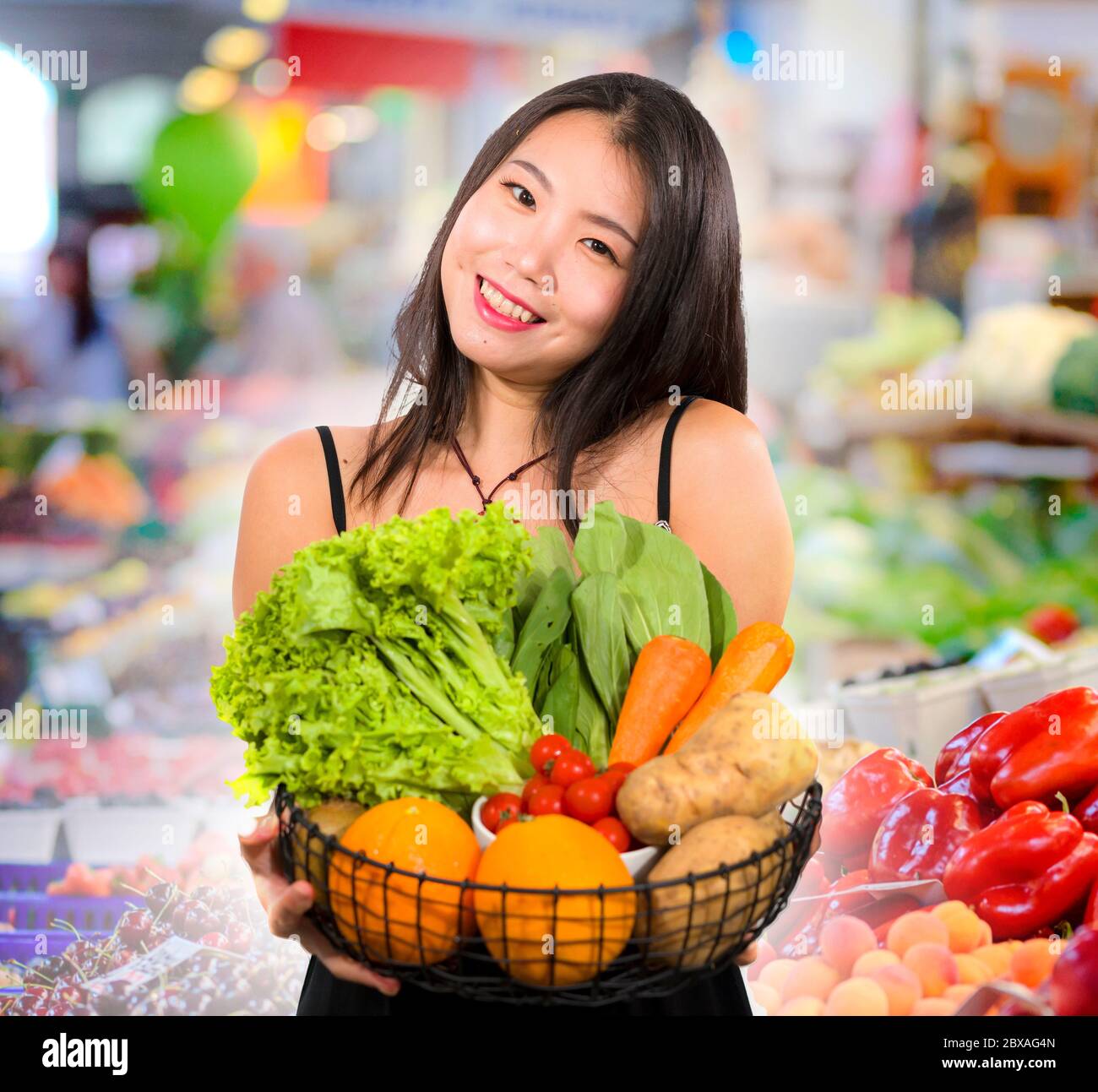 young happy and beautiful Asian Chinese woman holding basket full of ...