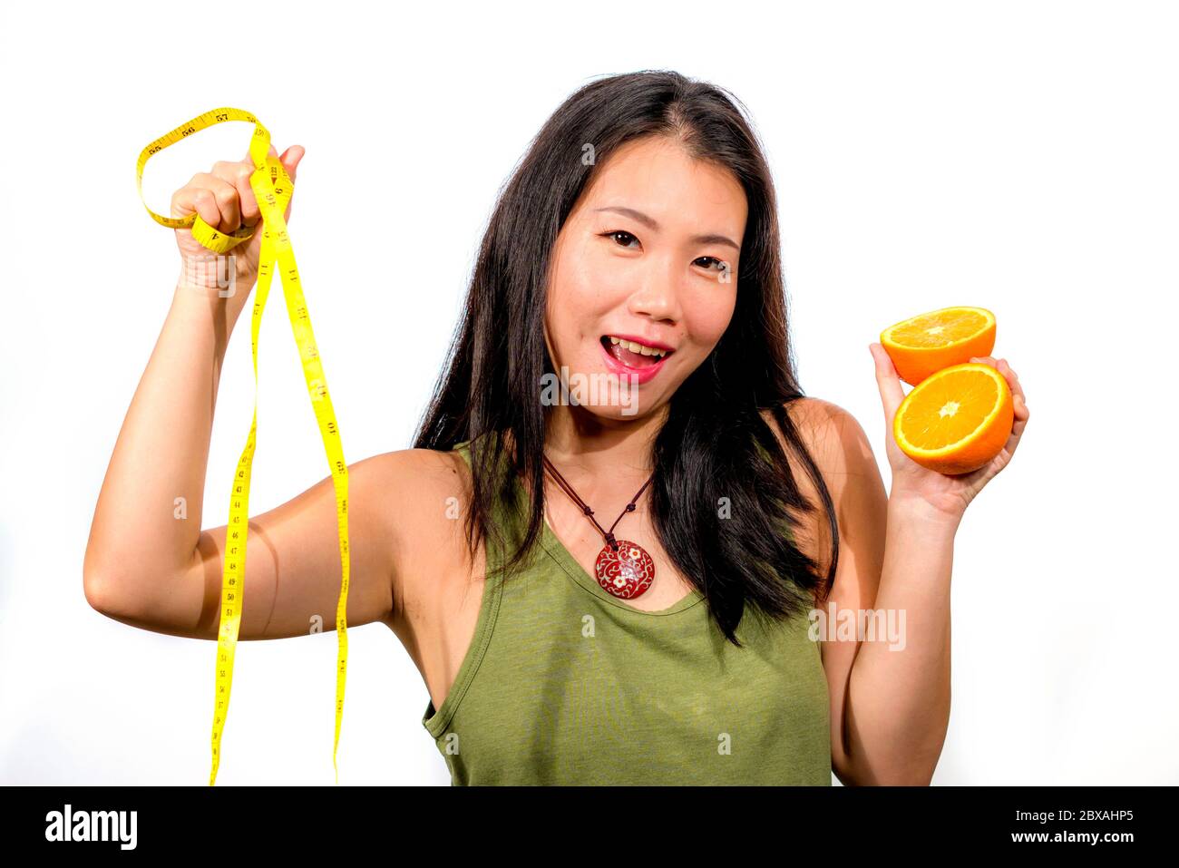 young happy and beautiful Asian Korean woman holding orange fruit and ...