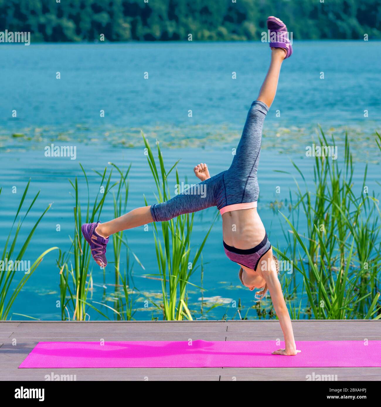 Fit sporty little girl in sportswear doing cartwheel exercise on the roll mat ba the lake Stock Photo Alamy