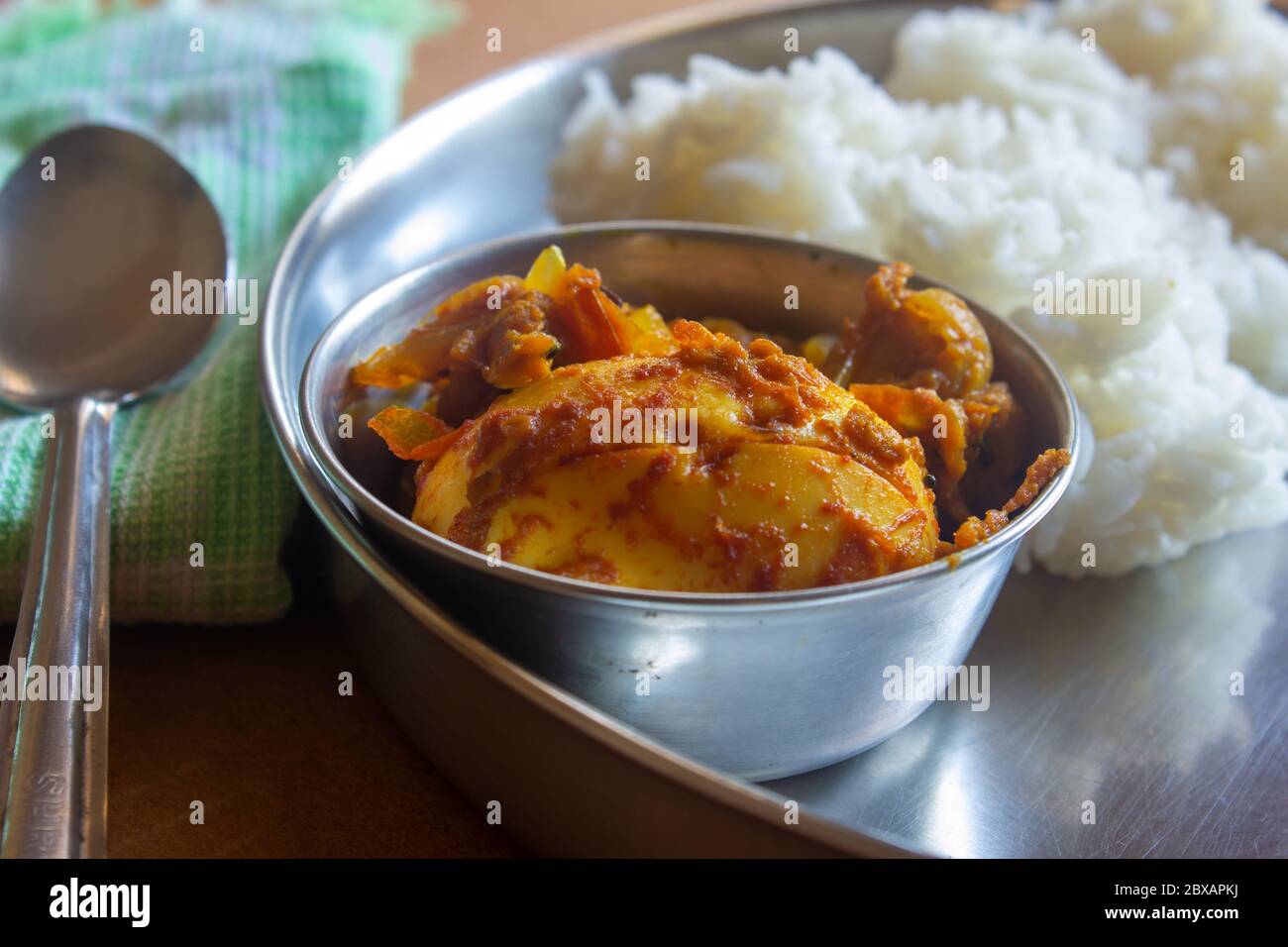 View of egg curry meal with white rice in background. Egg masala with