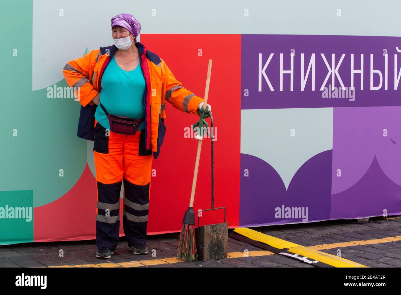 Moscow, Russia. 6th of June, 2020  An employee of the municipal utility service stays on background of the banner of the Red Square book festival in the center of Moscow, Russia. The inscription on the banner reads 'Book' Stock Photo