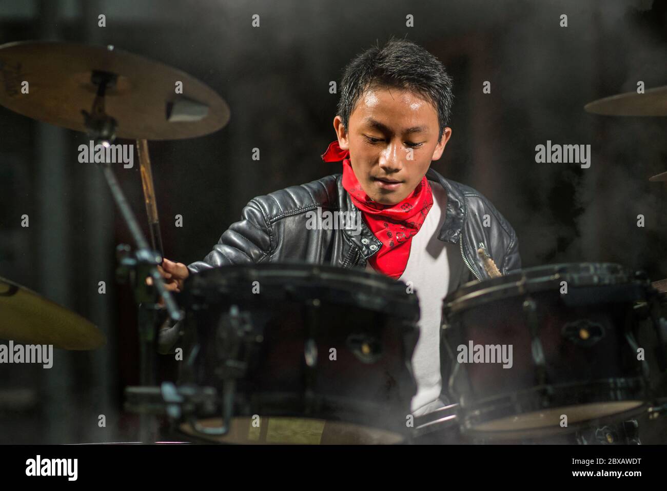 Teenager rock band musician . 13 or 14 years old cool and talented Asian  American mixed ethnicity boy playing drums in leather jacket and bandana  pra Stock Photo - Alamy