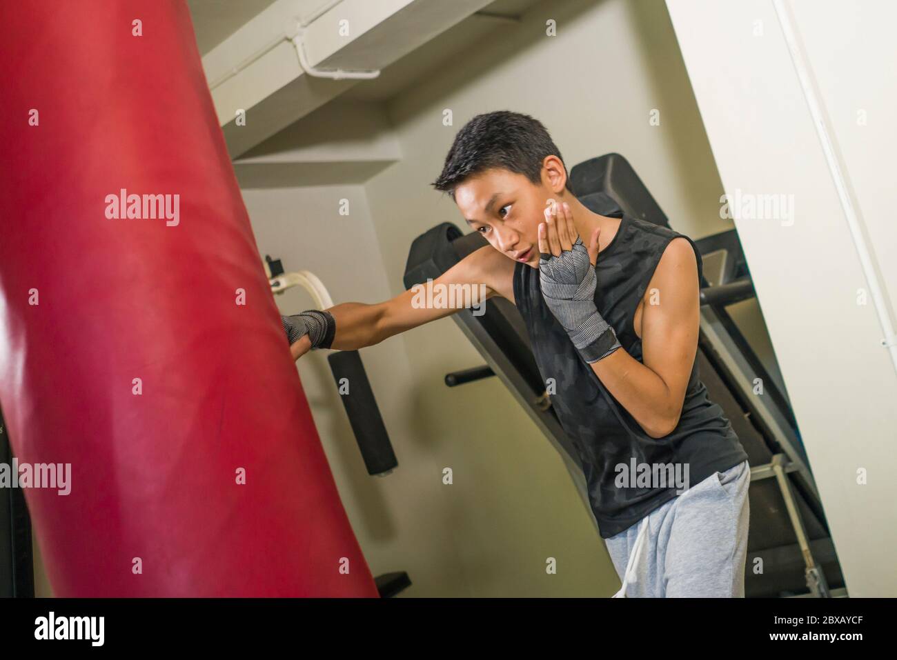Asian American teenager boxing on gym . young handsome and fierce 13 or 14 years old boy in