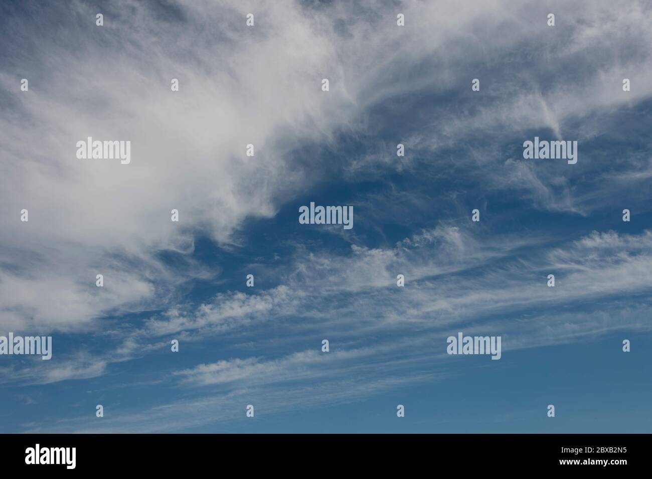 A bright blue sky with white whispy clouds Stock Photo