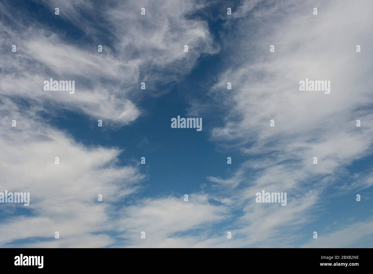 A bright blue sky with white whispy clouds Stock Photo