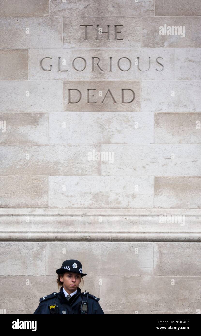 Female police officer stands in front of 'The Glorious Dead' monument in London's Whitehall district. England UK Stock Photo