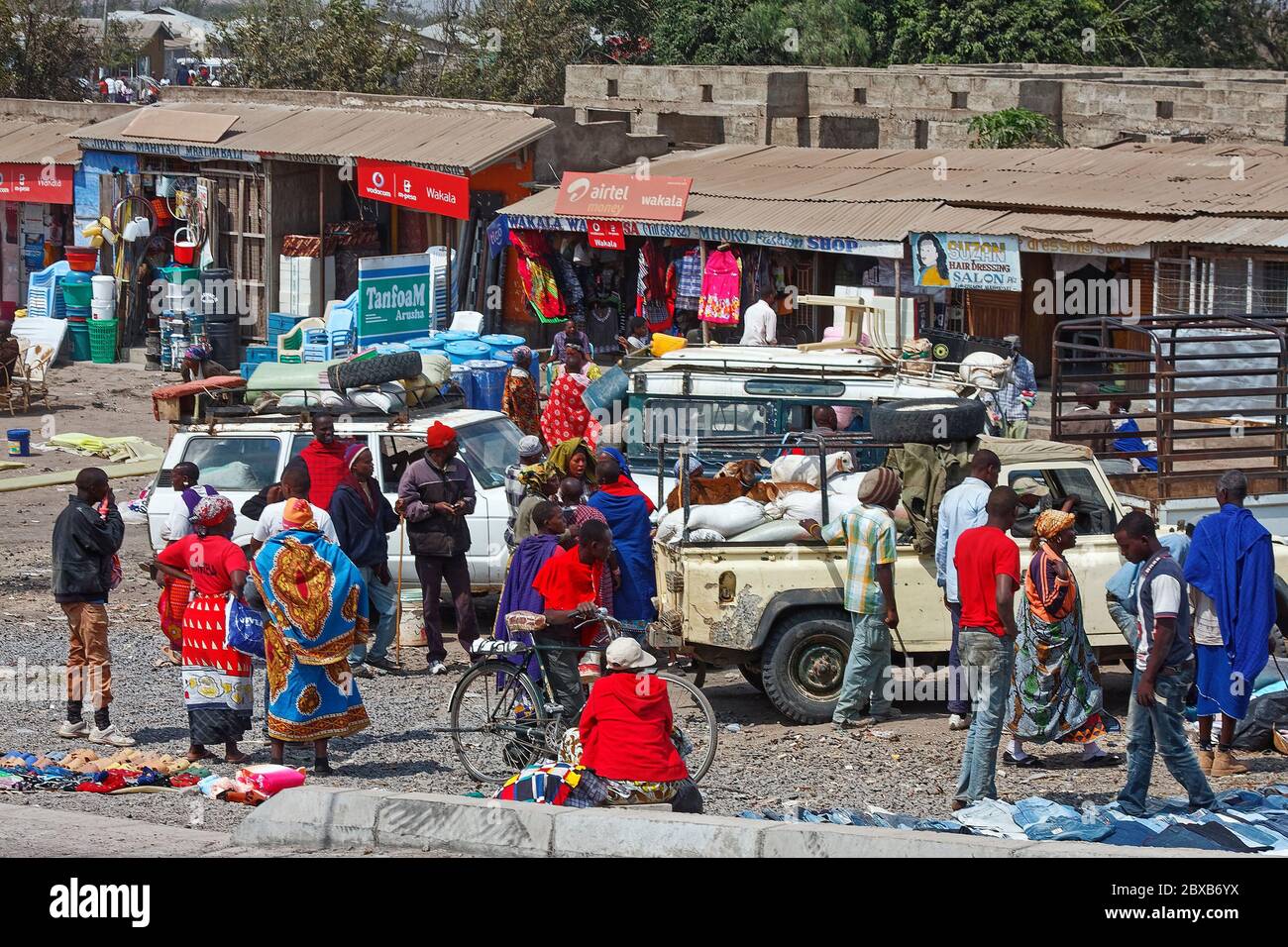 small shops, people, vehicles, clothing, household items, corrugated metal roofs, business, selling, Africa, Arusha; Tanzania Stock Photo