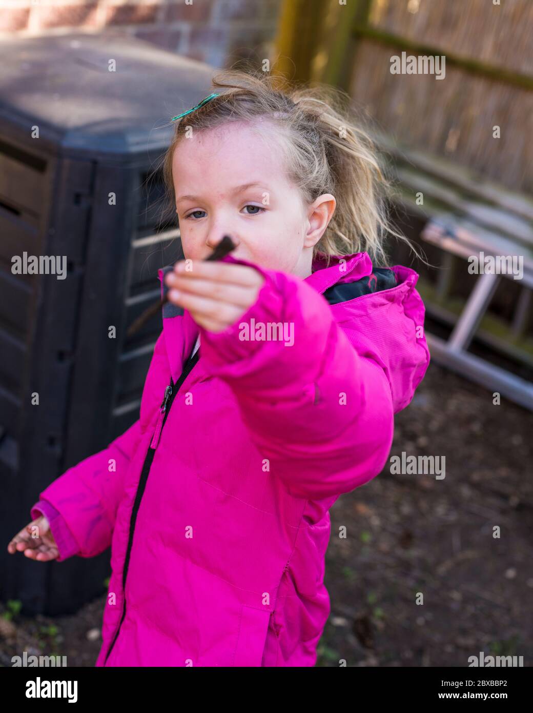 Corona composting, 4 year old pre-school girl emptying out the compost bin, getting your child interesting in gardening. Corona lockdown gardening Stock Photo