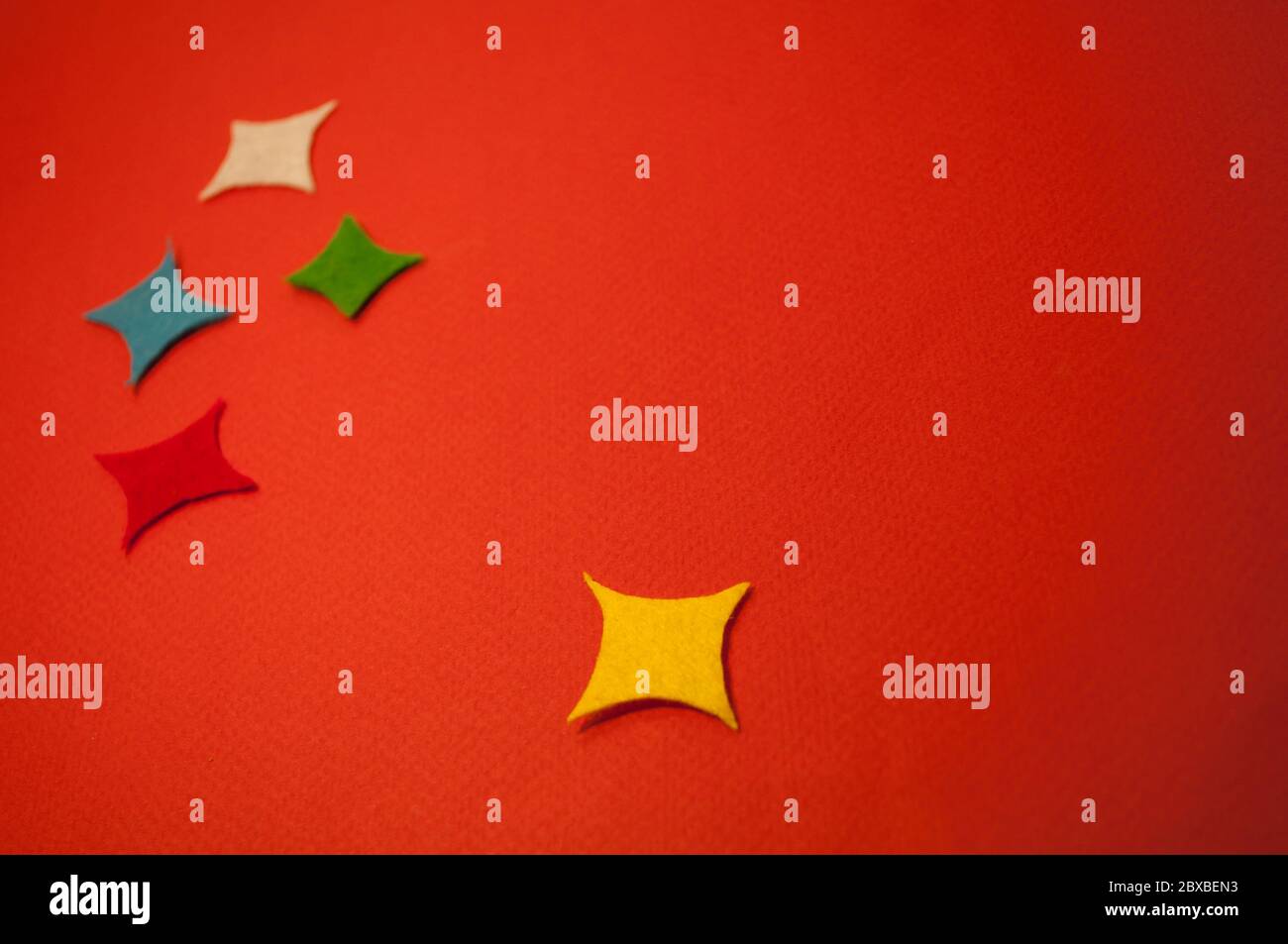 There are 5 rectangular colored stars on red cardboard. For background, with place for text Stock Photo
