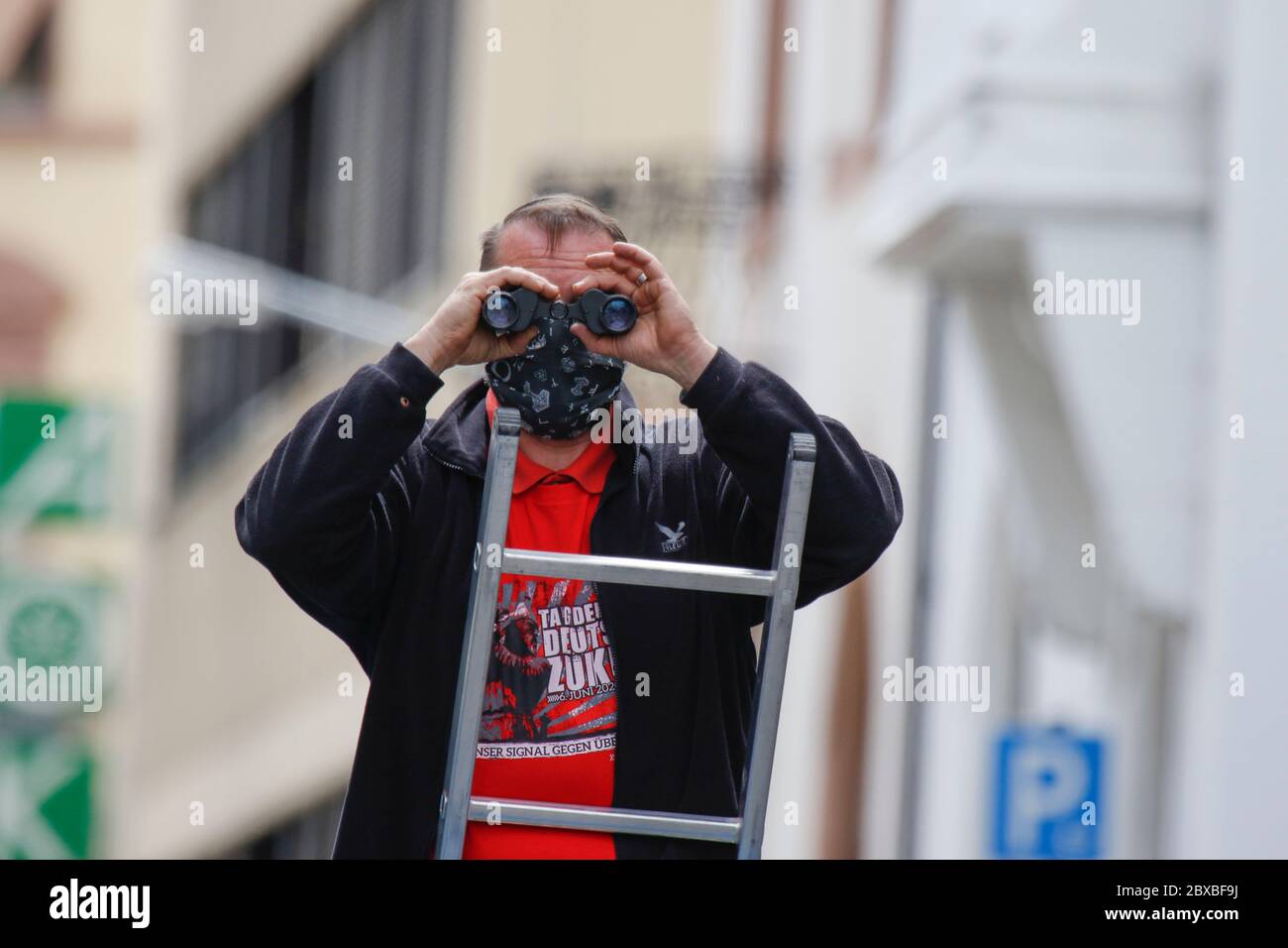Worms, Germany. 6th June 2020. A right-wing protester stands on a ladder, looking down the protest route with binoculars. Around 50 right-wing protesters marched through the city centre of Worms for the 12. and last 'Day of the German Future’. The march was cut short due to several hundred counter protesters who blocked the  path of the right-wing march. The march was a yearly right-wing event in different German city that drew over 1000 protesters at its high-point. Stock Photo