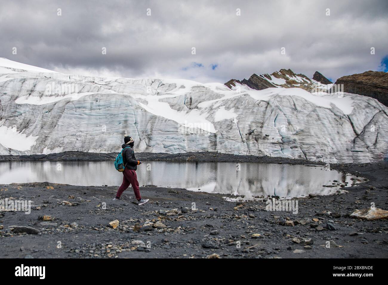 man walking in a glacier, little lake and cloudy Stock Photo