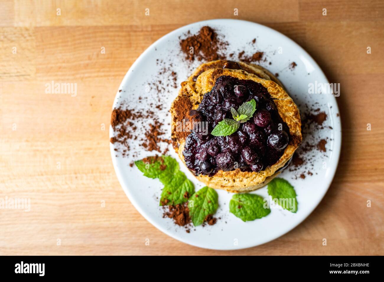 Delicious oats American pancakes with homemade chocolate toping, cooked blueberries and fresh mint leafs. Healthy lifestyle cooking Stock Photo
