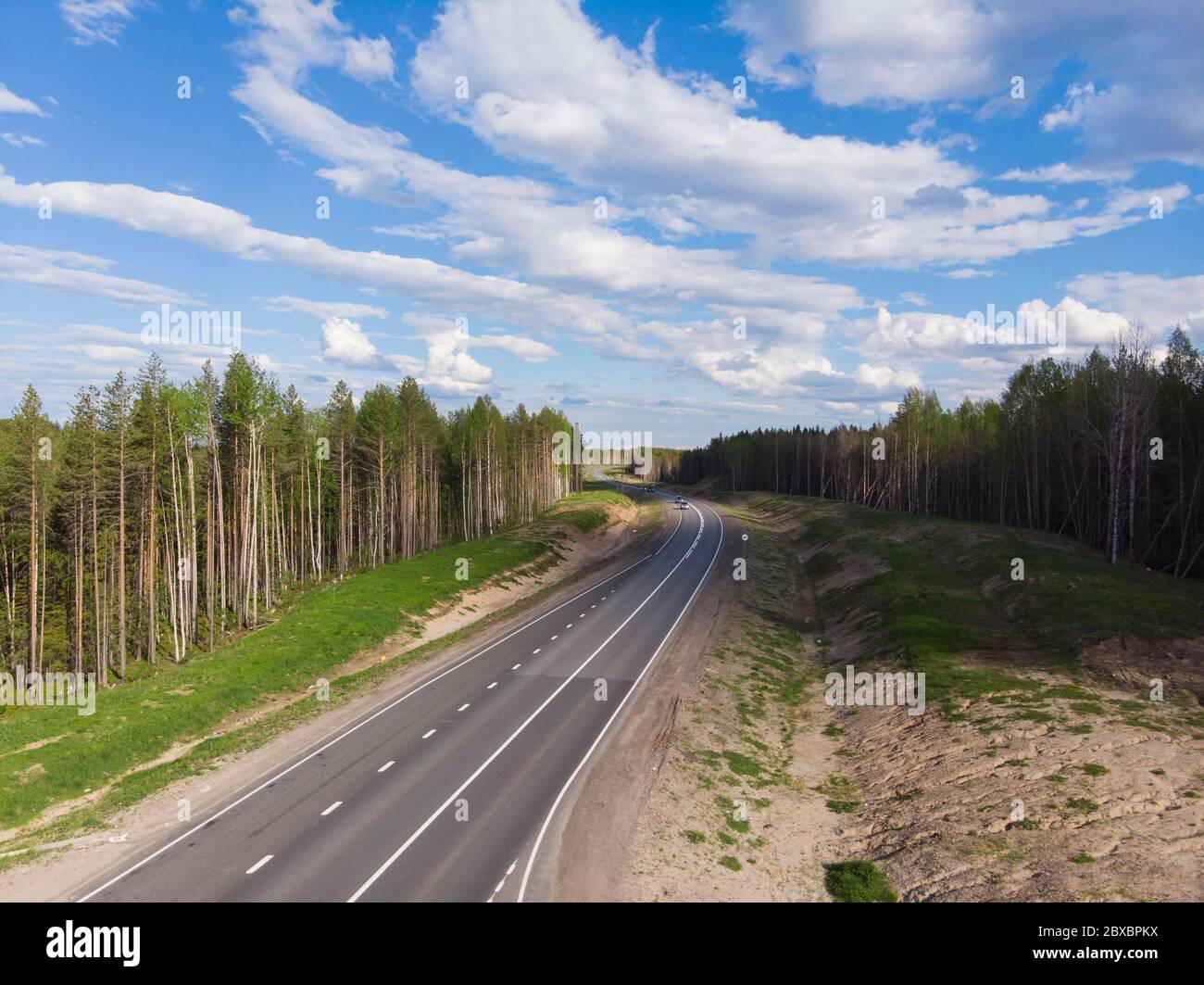 Asphalt road through a dense forest. Car trip Stock Photo