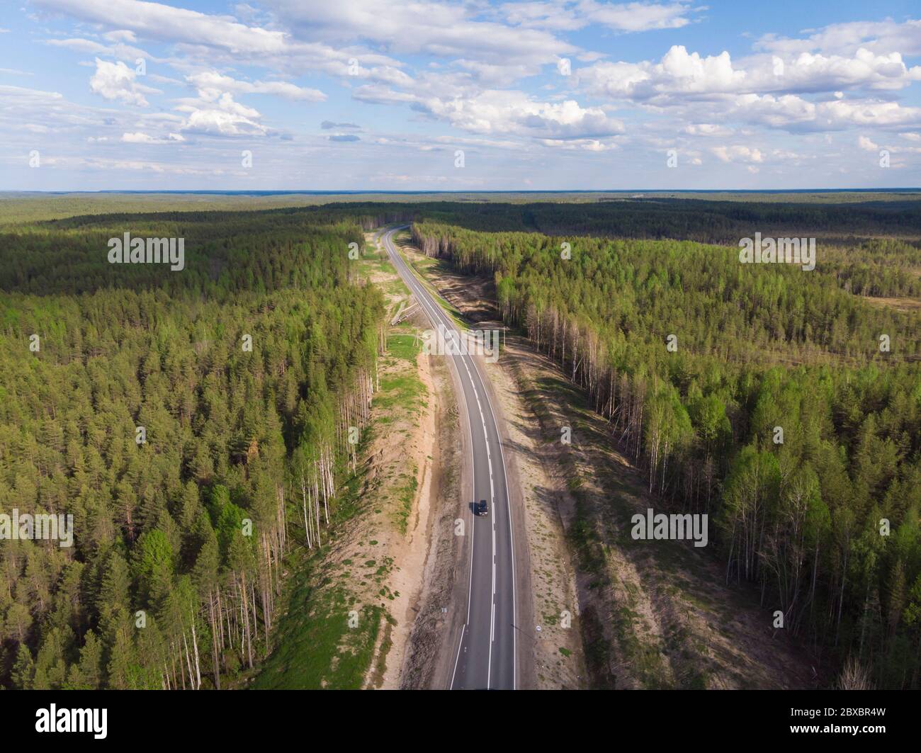 Asphalt road through a dense forest. Car trip Stock Photo