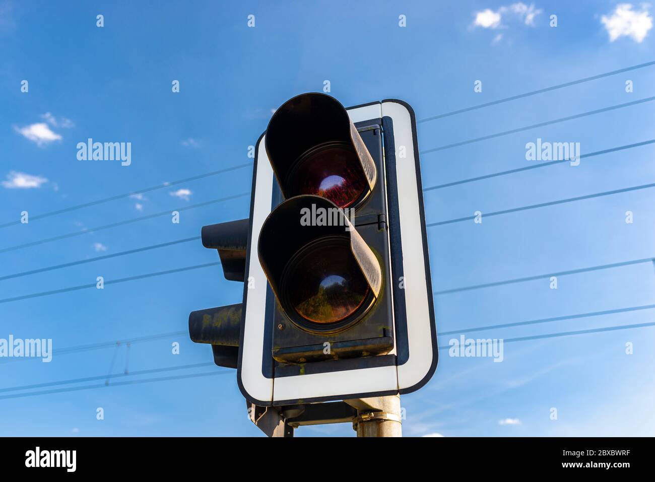 Traffic lights before the railway crossing with a red light to warn of approaching trains. Stock Photo