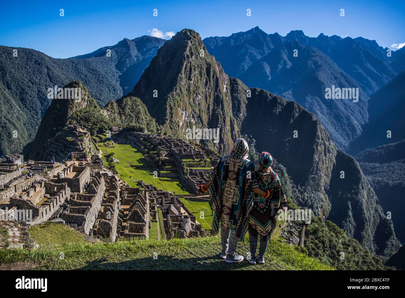Couple standing, back to camera, watching the beautiful machu picchu ruins in Peru. Stock Photo