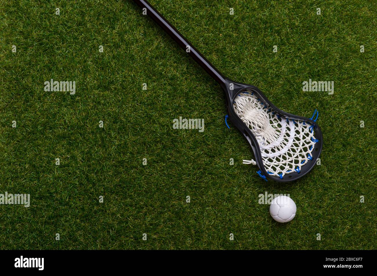 Lacrosse stick and white ball on grass background. Lacrosse is a team