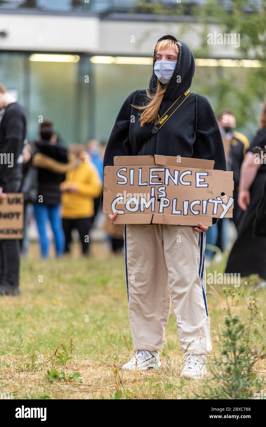 Black Lives Matter anti racism protest demonstration in Southend on Sea, Essex UK. White Caucasian female with silence is complicity placard. Isolated Stock Photo