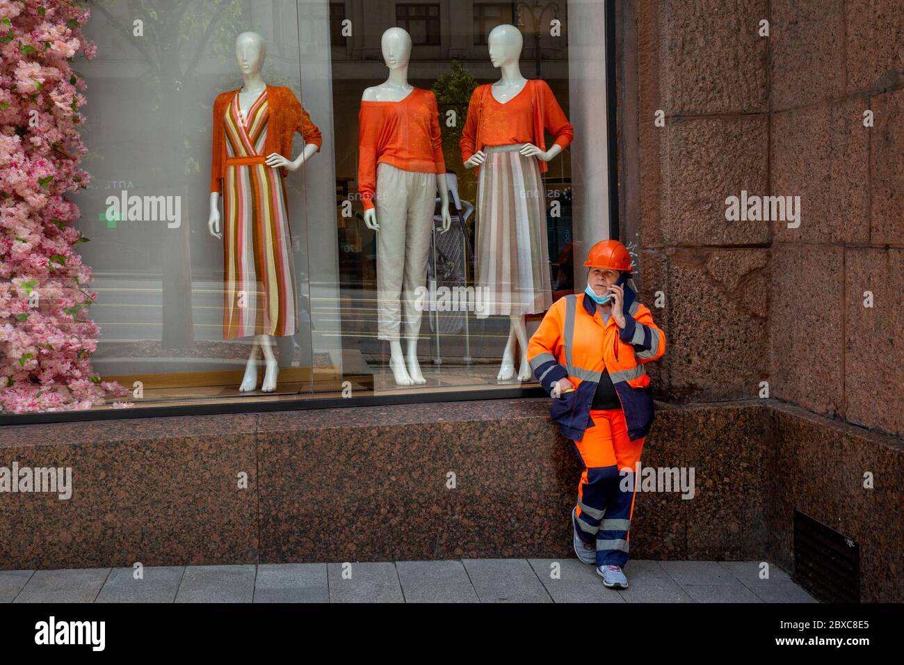 Moscow, Russia. 6th of June, 2020 An employee of the municipal utility service talks by a cellphone near the window of a fashion store on Tverskaya street in the center of Moscow, Russia Stock Photo