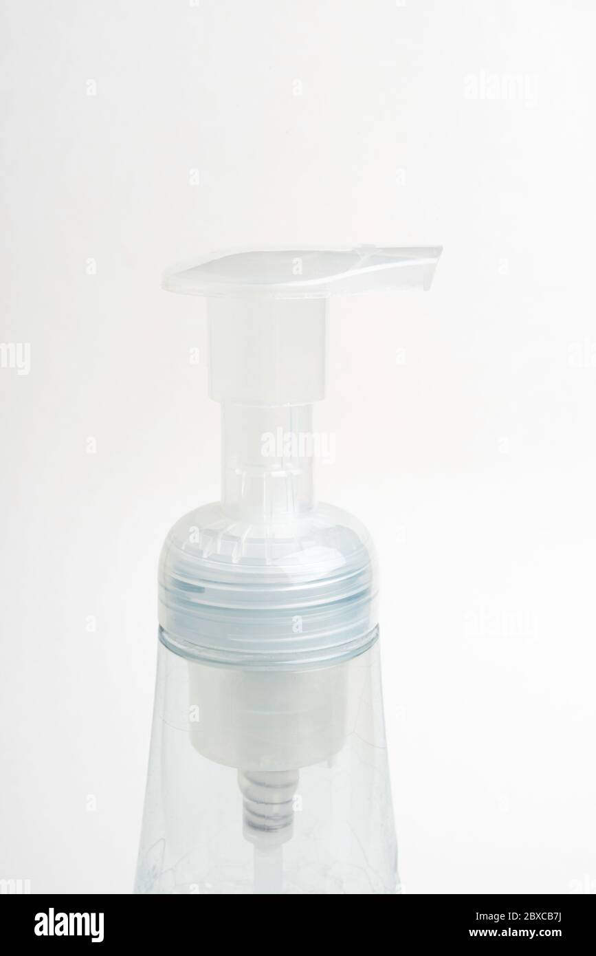 A close-up image of the translucent top pump and bottle of a foam soap plastic dispenser set on a white background. Stock Photo