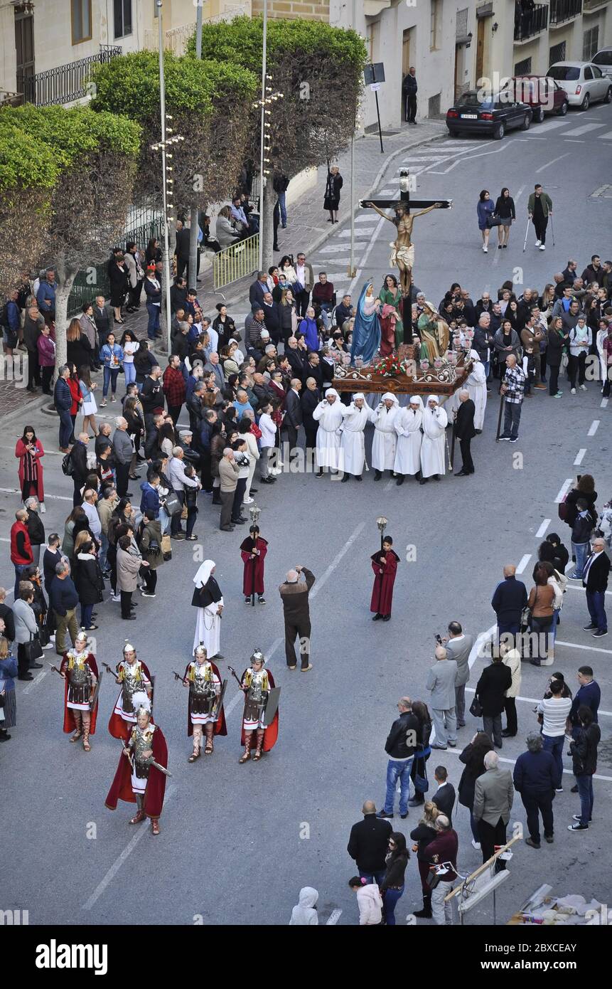 Bird view of scene bearers, dressed in white. They are carrying a stage with Jesus on the cross on it. Five men dressed in Roman uniforms are in front Stock Photo