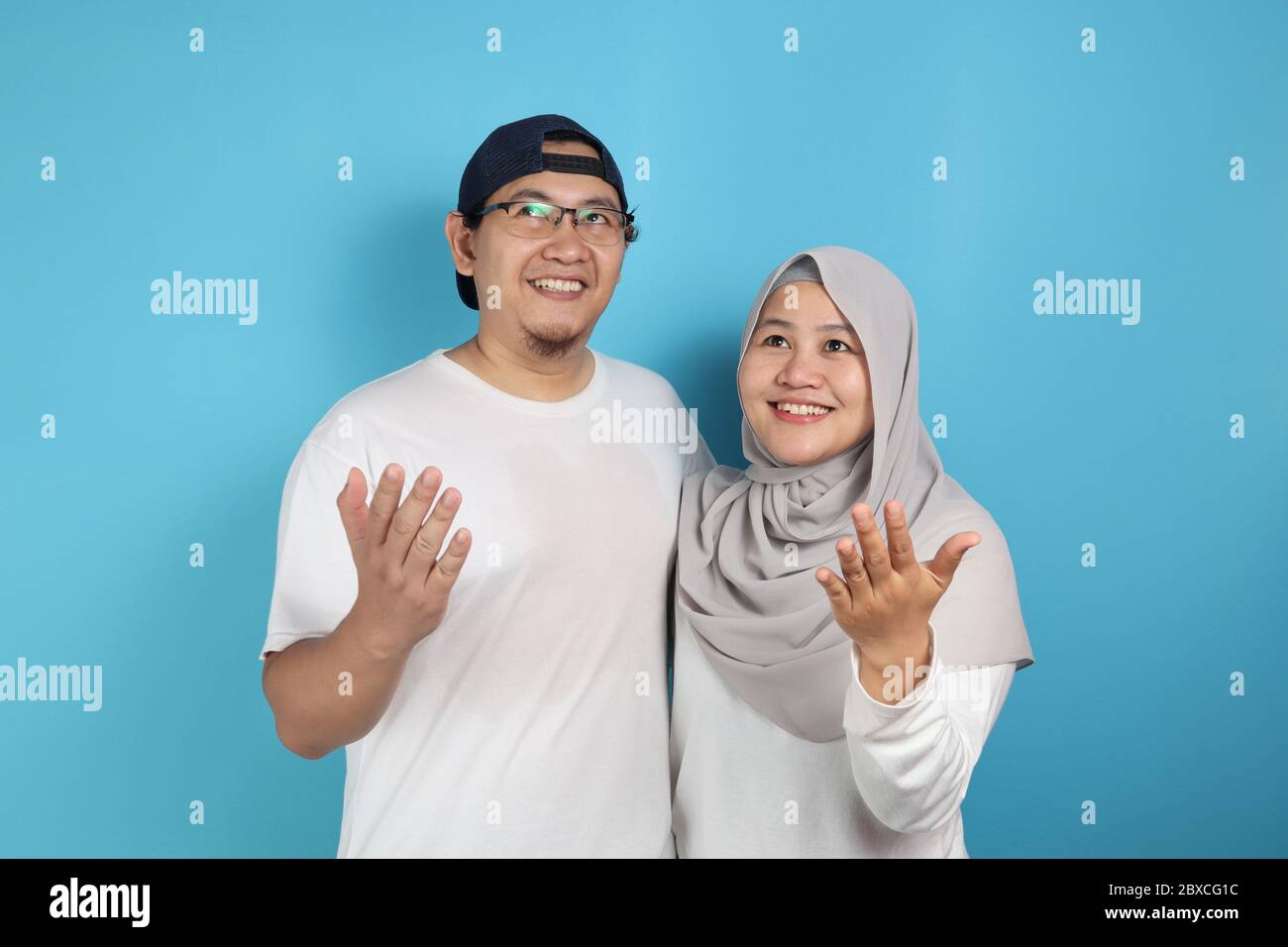 Portait of happy Asian muslim couple smiling, looking up and dreaming, husband and wife hugging full of love, family concept Stock Photo
