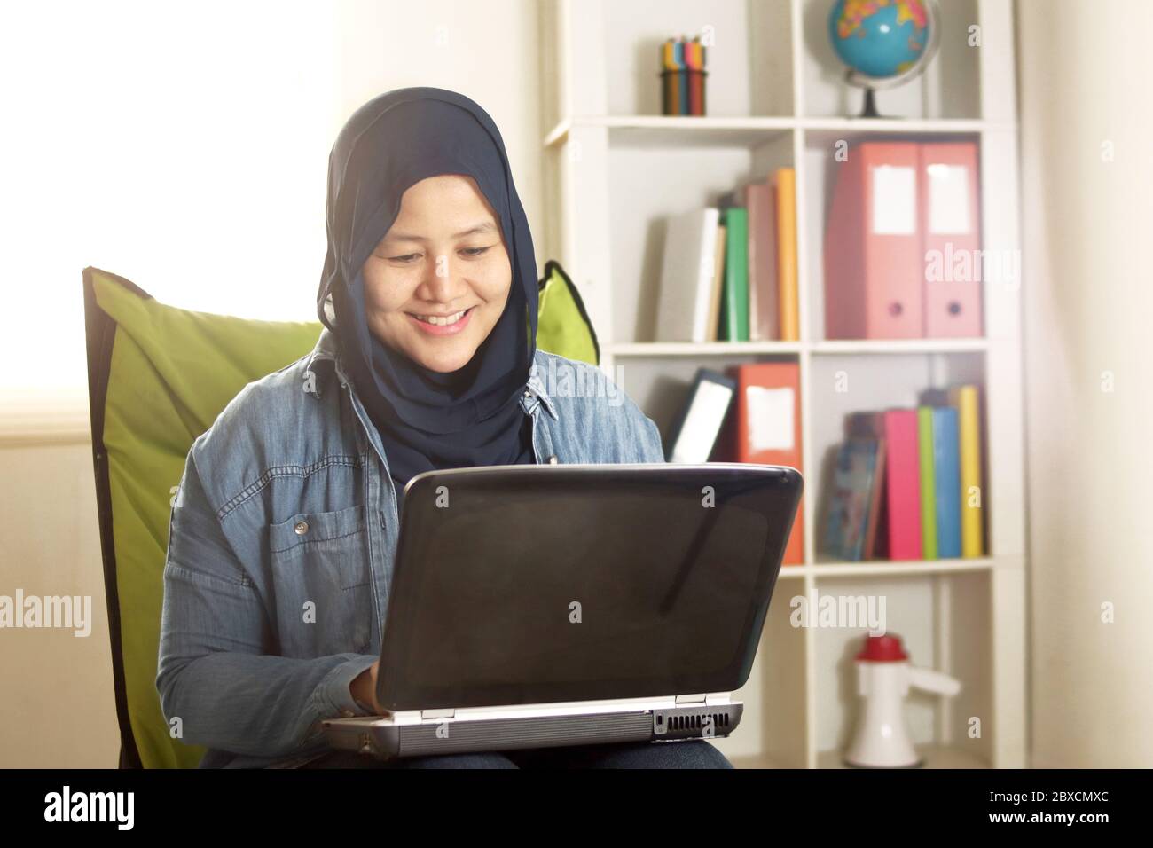 Portrait of happy smiling Asian muslim woman working with laptop in her ...