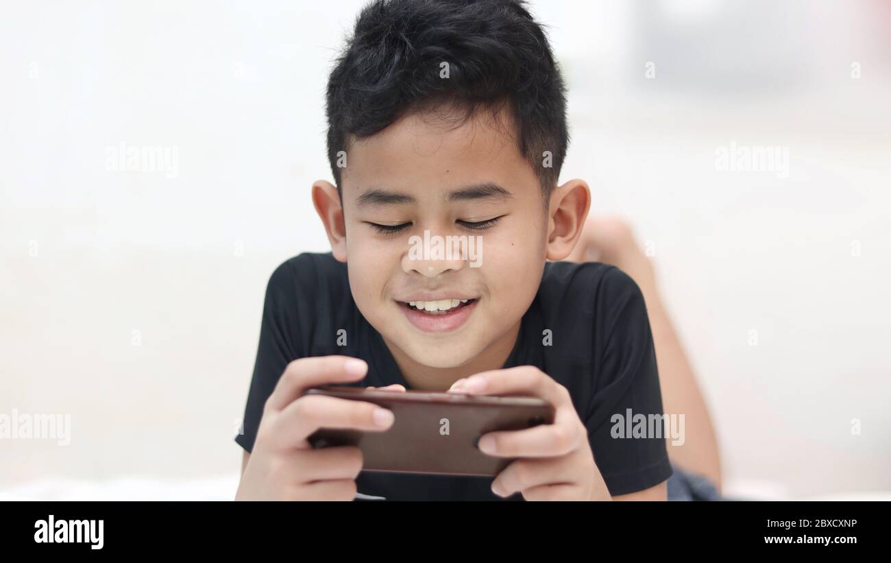 Asian Boy Playing Cell Phone Les Mains Des Enfants Tiennent Un Smart  Phonetabletcellphone Pour Jouer Et éduquer Un Enfant De 2 Ans Allongé Sur  Une Table Blanche